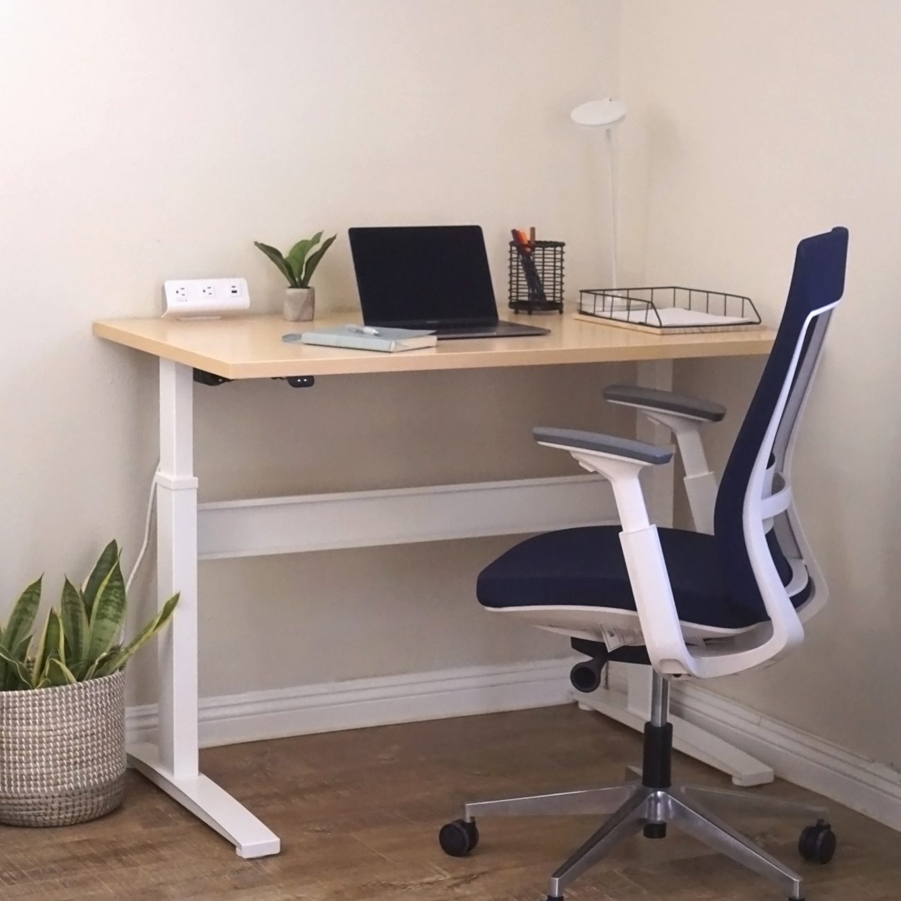 RightAngle Bonita height-adjustable desk with a maple top and white T-legs set into a corner