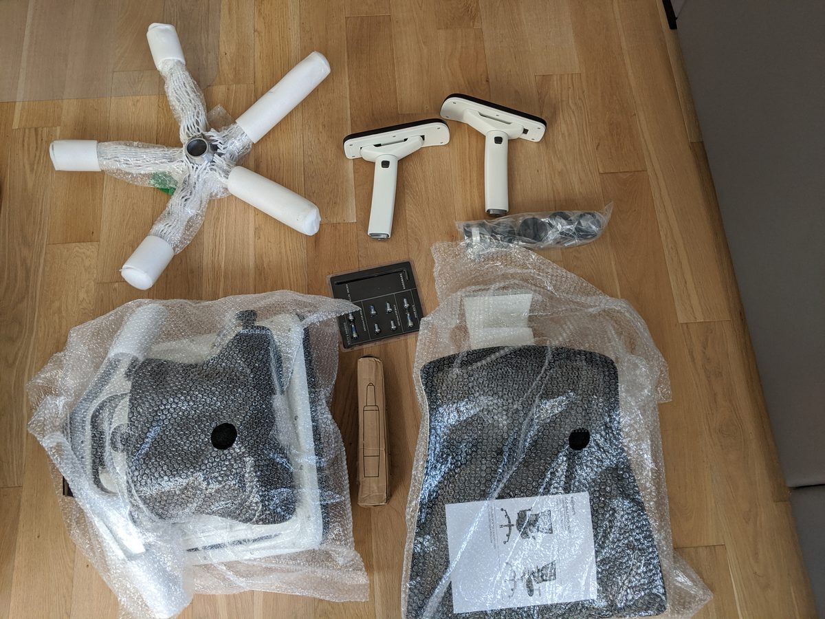 Eurotech iOO parts unpacked on the floor: five-star base, castors, armrests, seat and back
